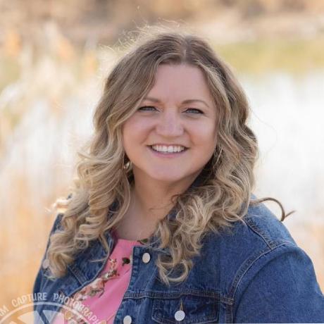 Kelsey smiling outdoors in a denim jacket